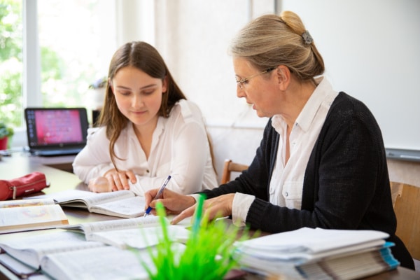 Teacher and student sat at a desk going through notes.