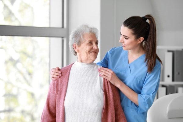 Elderly lady and medical worker stand together smiling