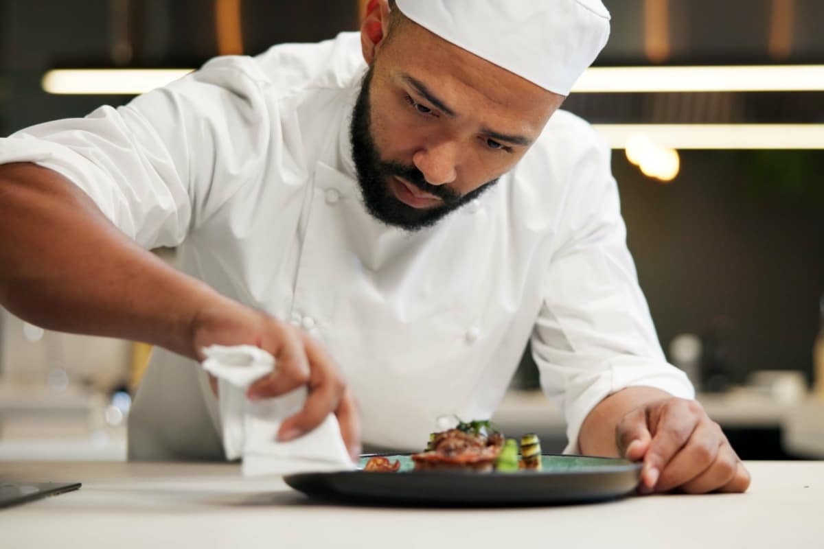A male chef, plating up food in a restaurant kitchen
