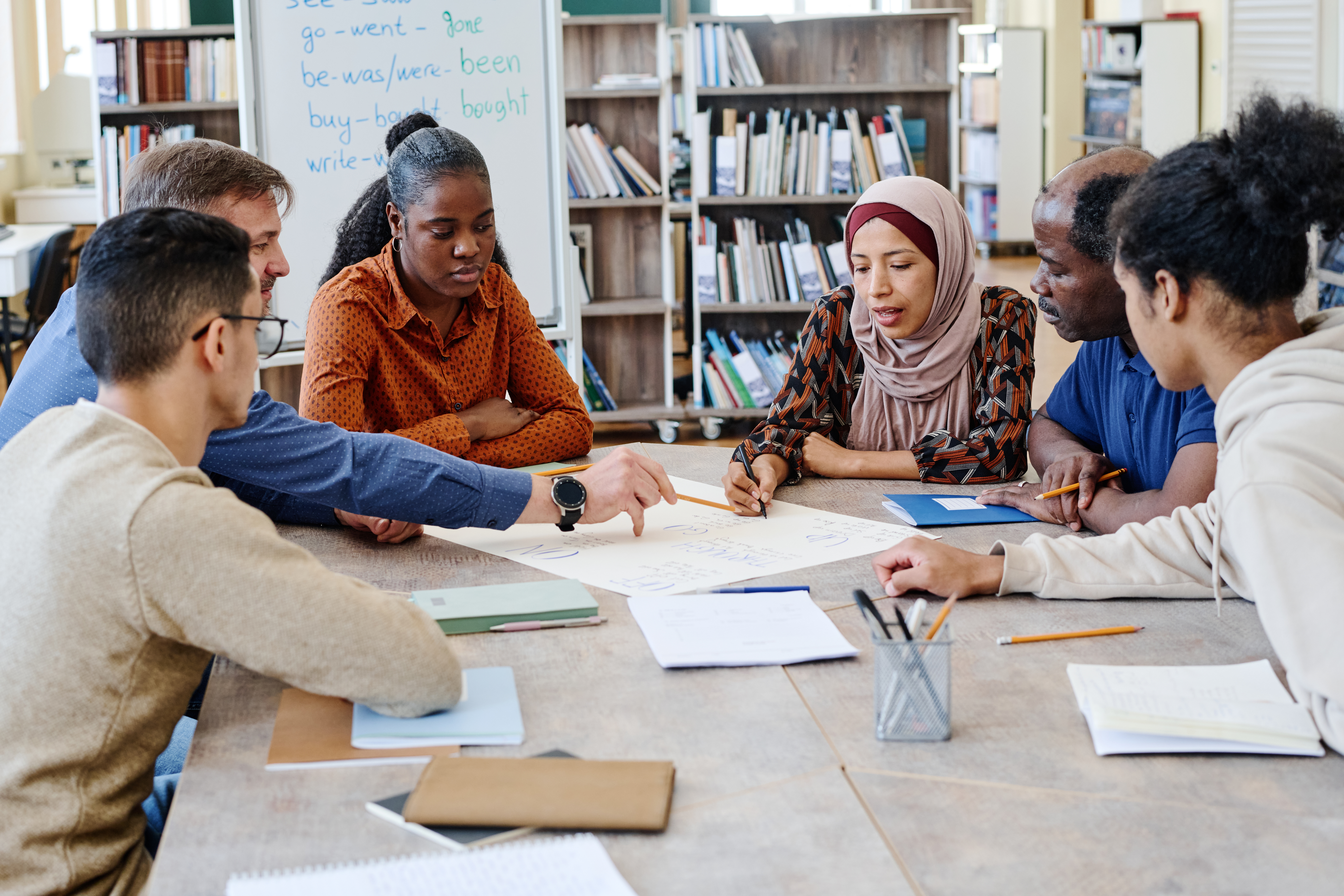 A group of people sat around a desk, looking at a large sheet of paper making notes or brainstorming.