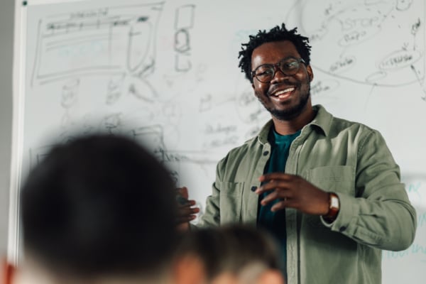 Male teacher, stood in front of white board addressing his classroom