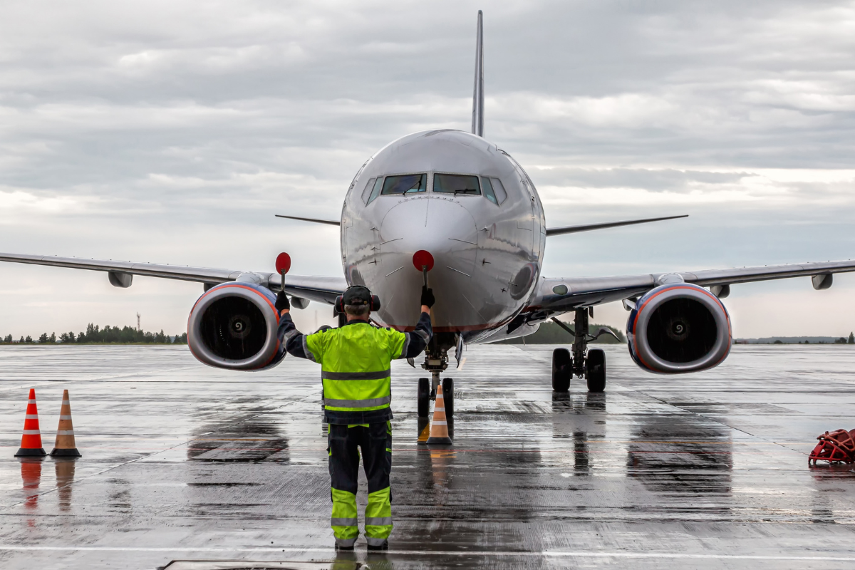 Airplane marshalling at the airport apron in rainy weather.
