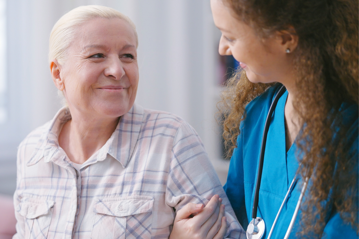 Care worker helping senior woman to stand up and take a walk