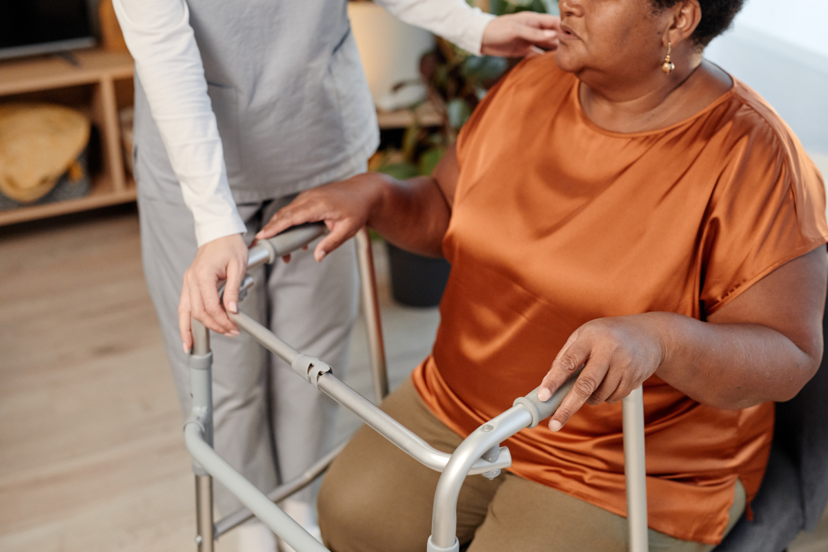 woman using walker receiving assistance from a care worker