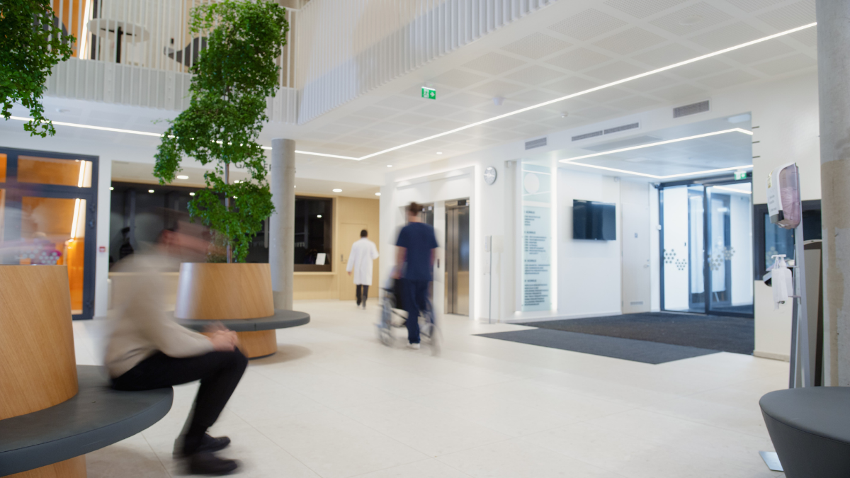 Motion blur in modern hospital lobby with a busy flow of patients, visitors, and staff.