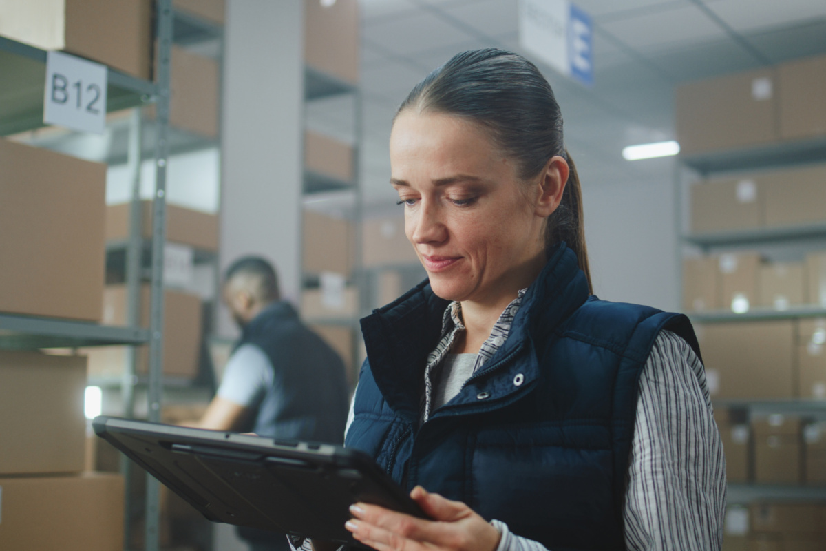 Female facilities manager in warehouse facility: uses tablet computer